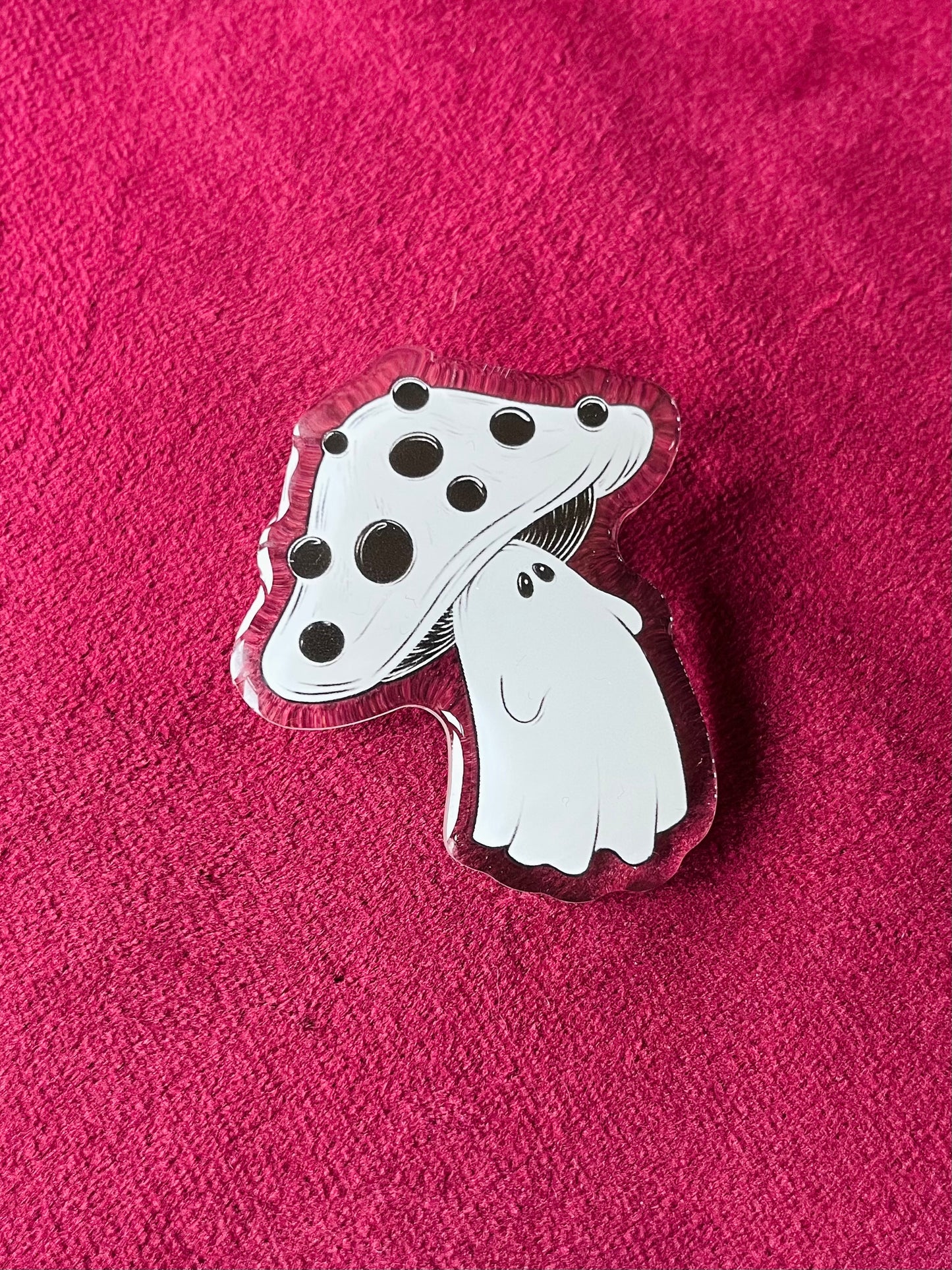 Mushroom-shaped pin with black spots on a pink textured background