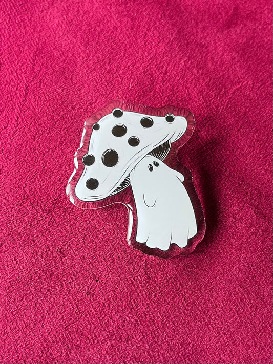 Mushroom-shaped pin with black spots on a pink textured background